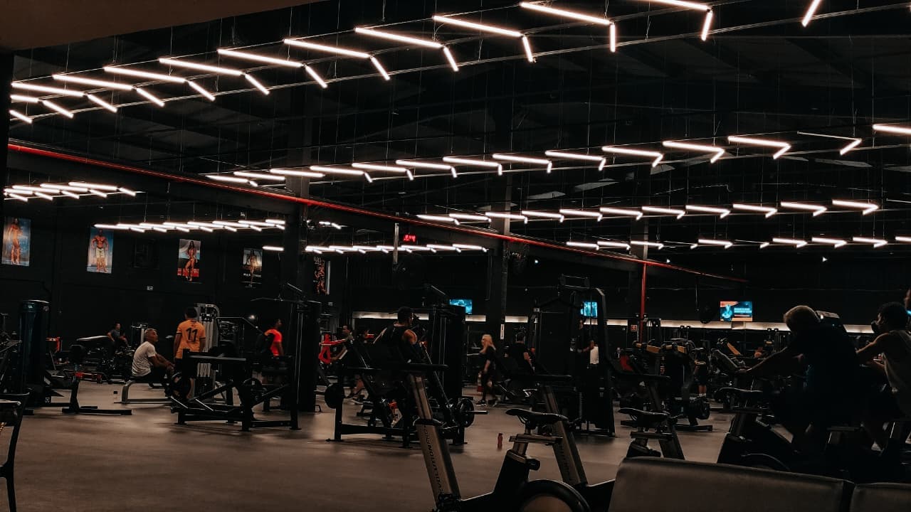 Salão do CT Forma Fit à noite, com iluminação em LED e alunos treinando